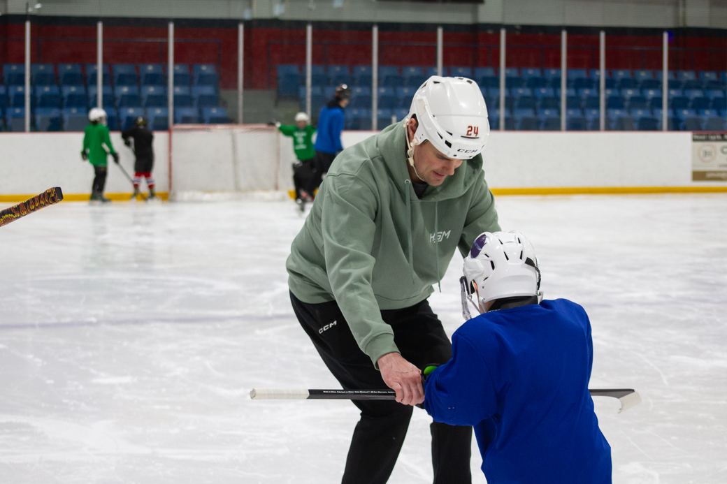 A coach guiding a camper through a puck drill at centre ice