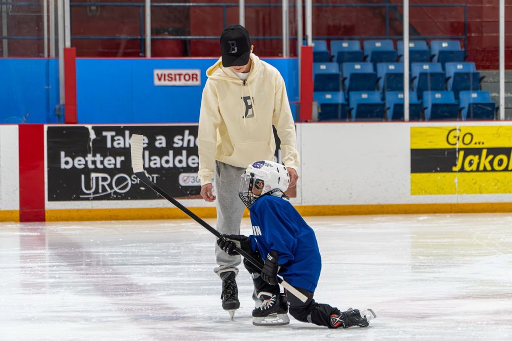 Two beginners in blue helping each other stay upright near the blue line