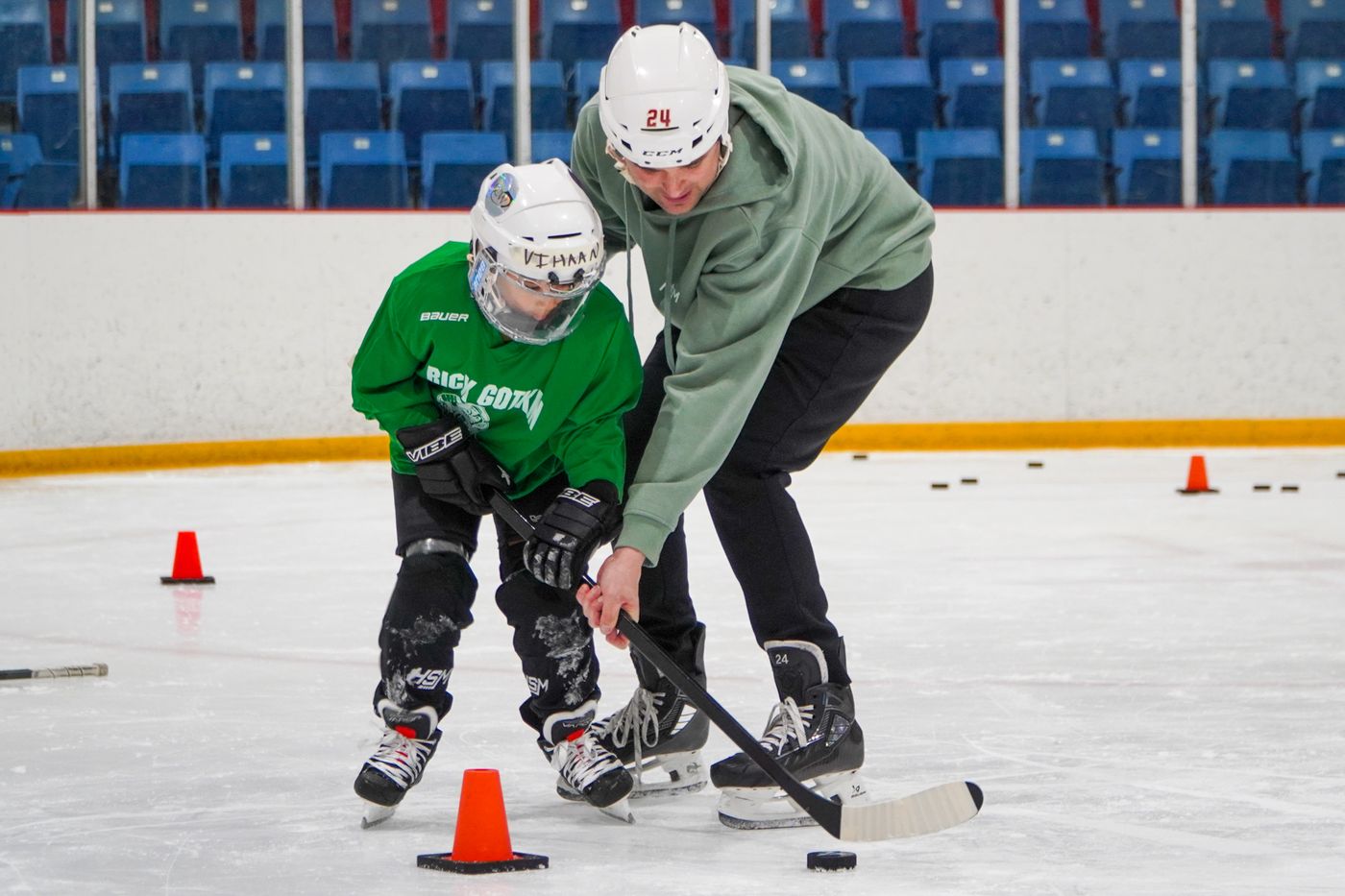 Campers weaving a puck through orange cones with a volunteer guiding them
