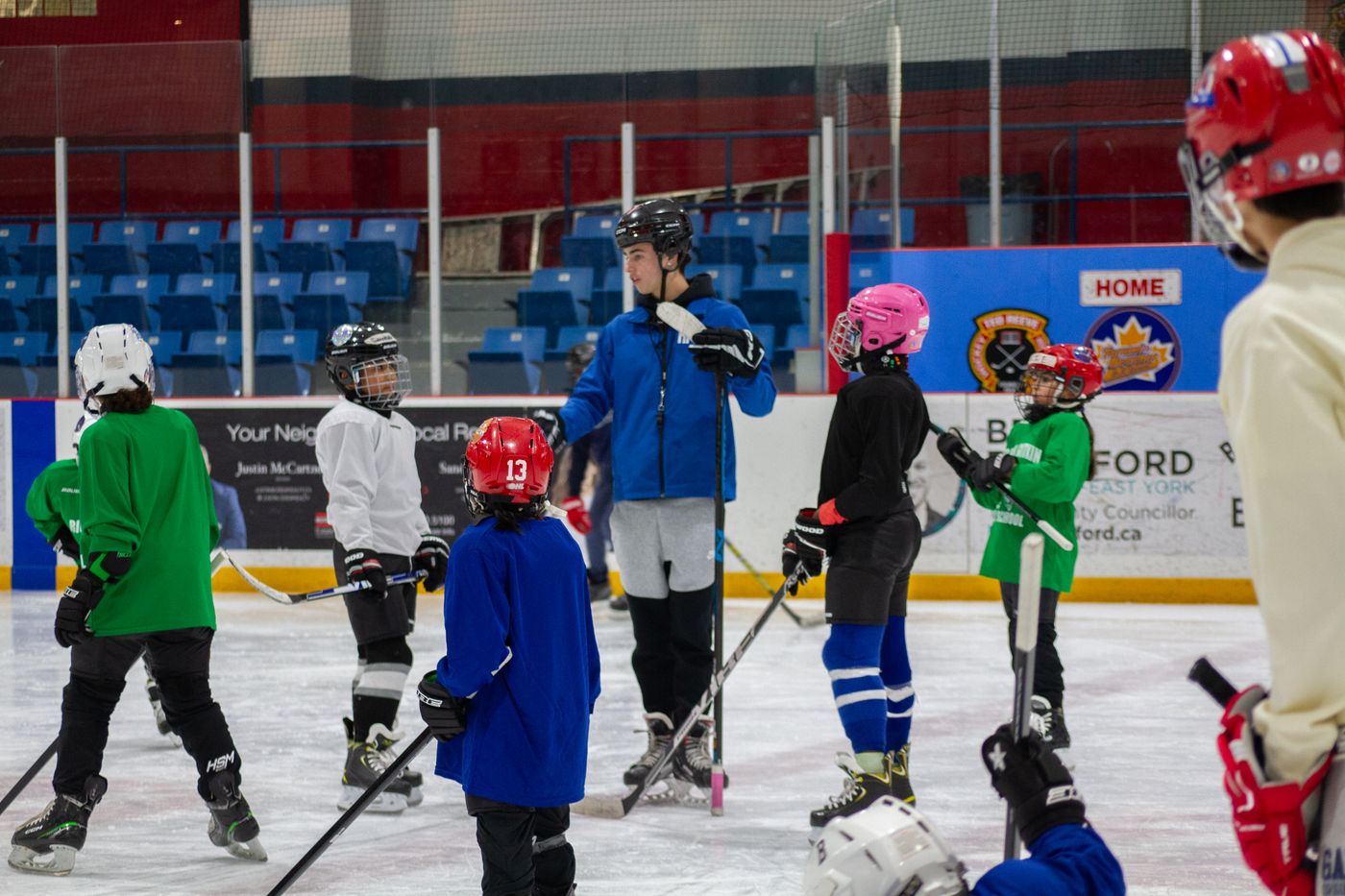 A line of campers in helmets and jerseys standing along the boards waiting for a drill to start