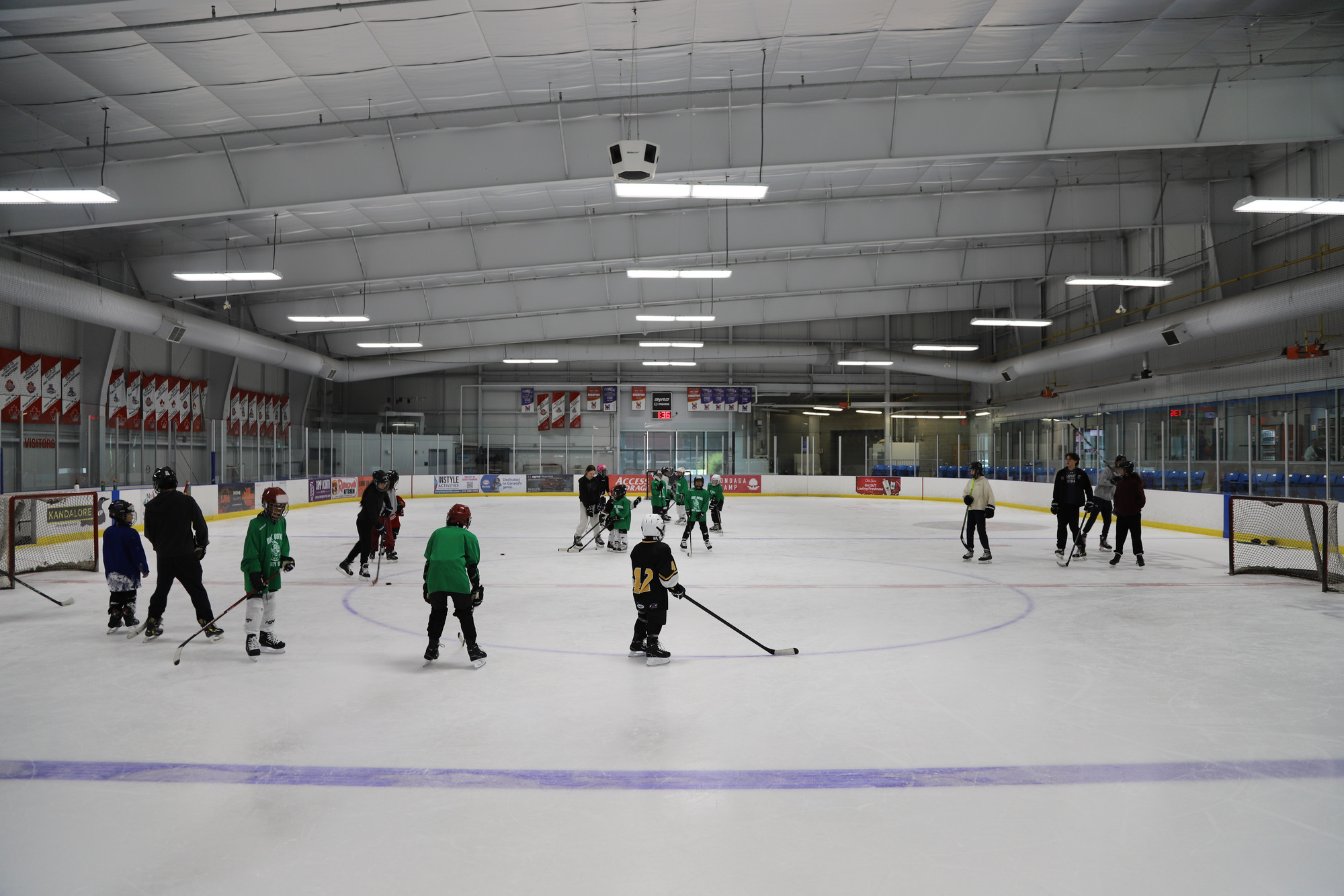 A wide view of the rink partway through a session, campers spread across the ice