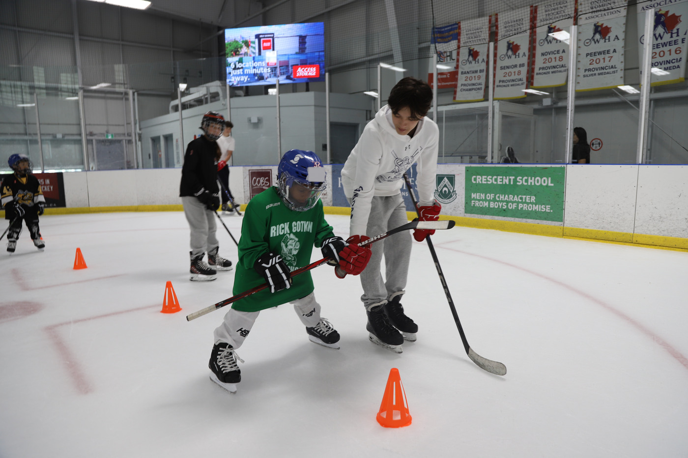 A volunteer guiding a young camper through a line of orange pylons at Leaside Arena